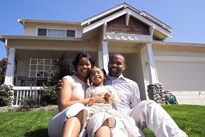 family sitting outside home smiling at camera